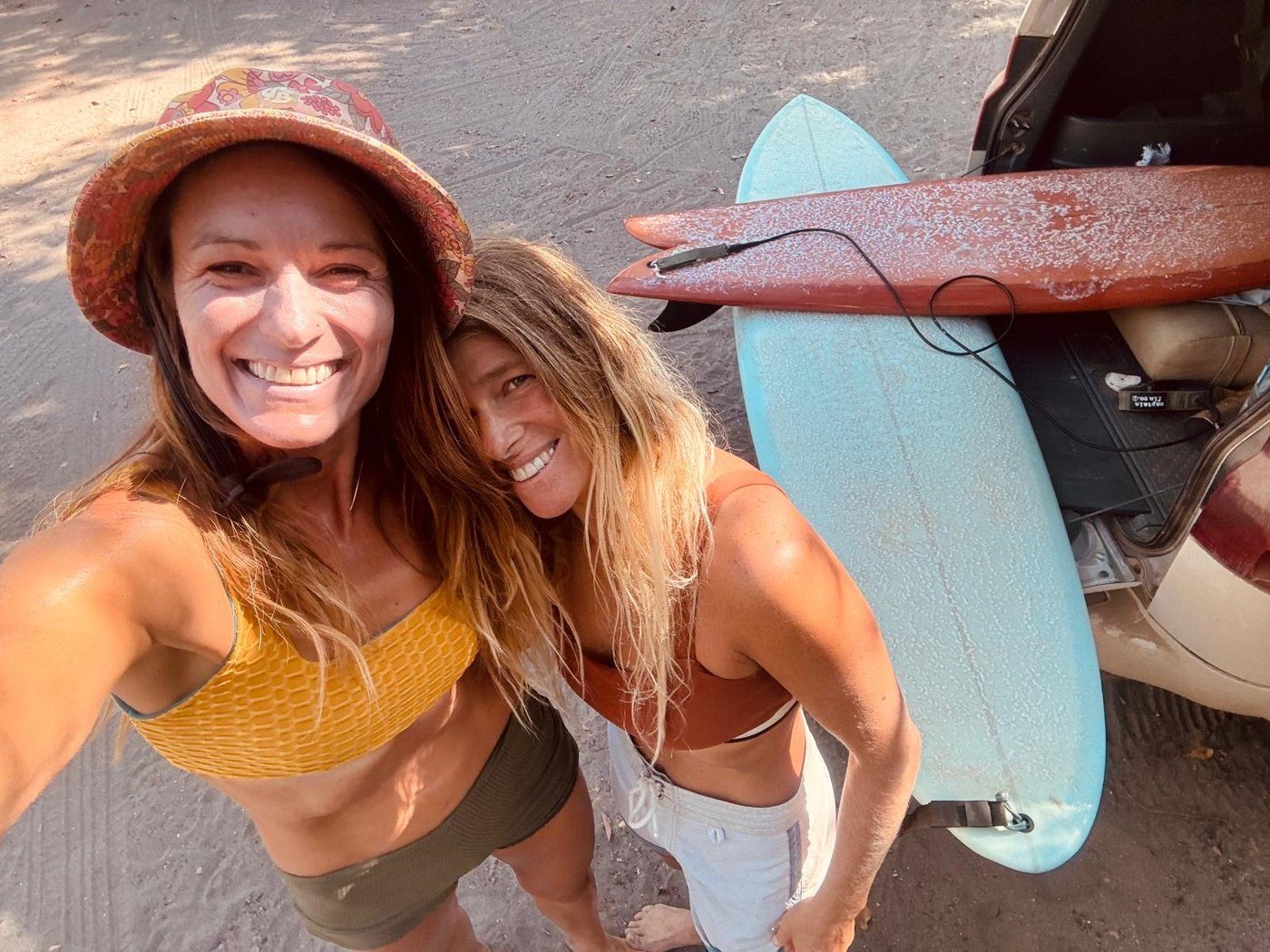 Two surfers with longboards on a truck at the beach in La Saladita