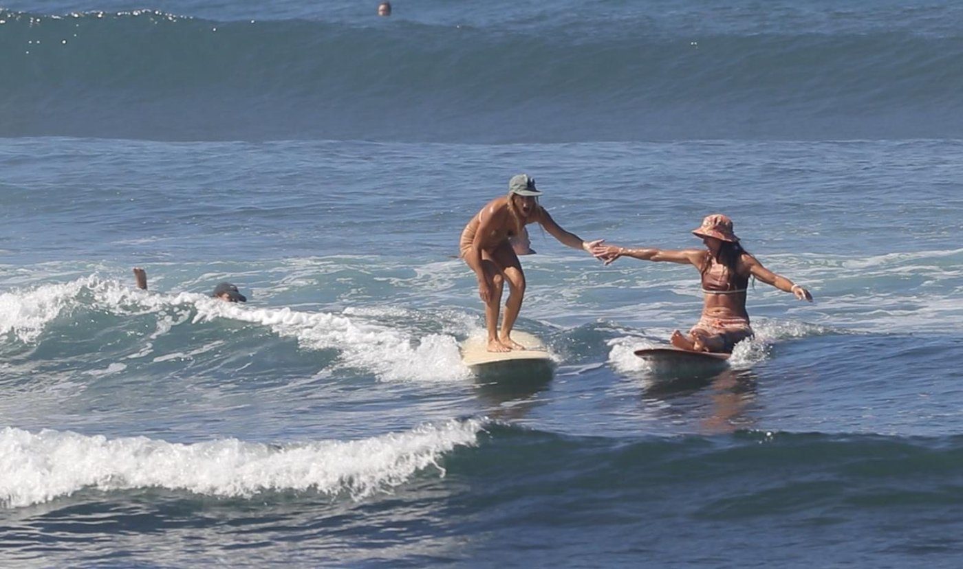 Two surfers riding the same wave together at La Saladita, hands joined